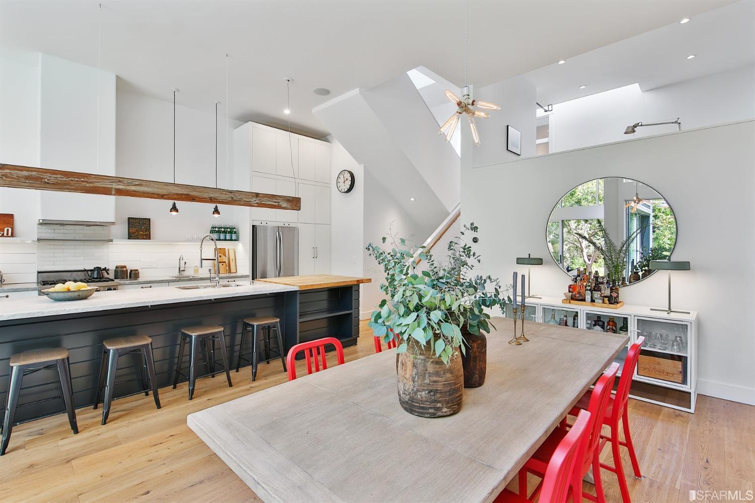 SF REALTY - Dining table with red chairs off a chic white and wood kitchen